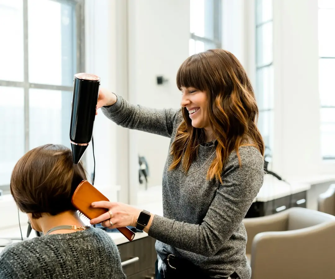 Friseurin föhnt einer Kundin die Haare